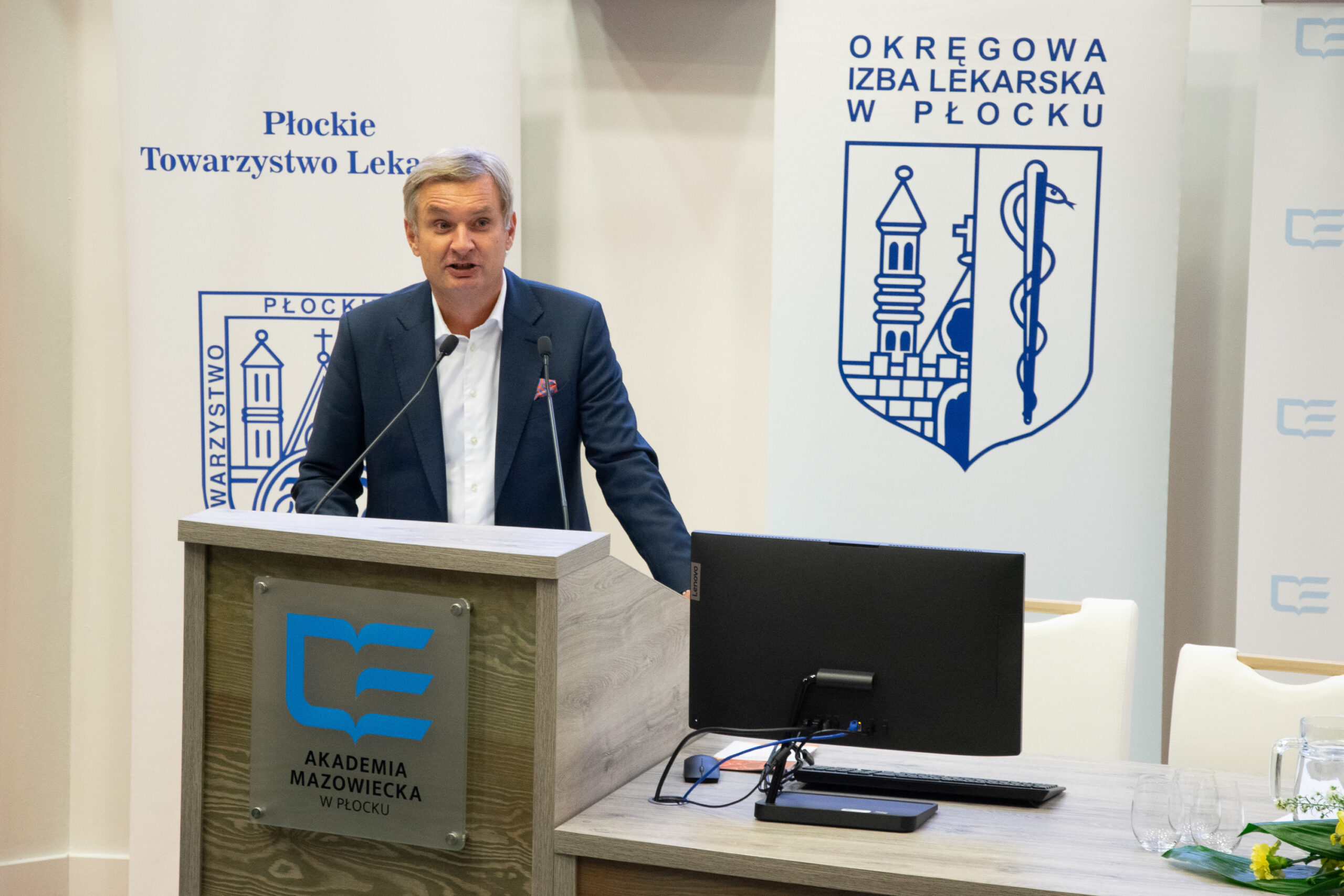 mężczyzna wygłaszający przemówienie przy ambonie do mikrofonów