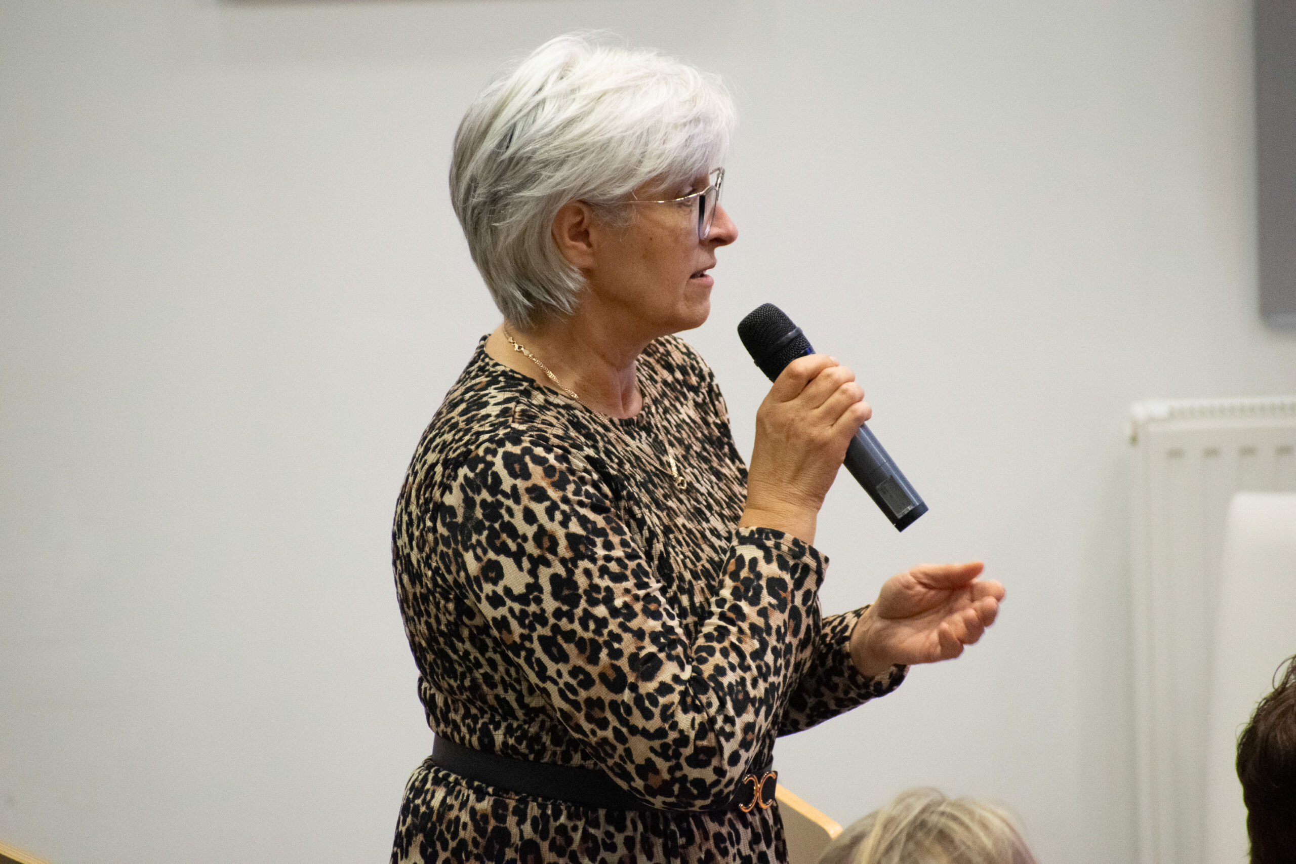 kobieta stojąca bokiem, mówiąca do mikrofonu