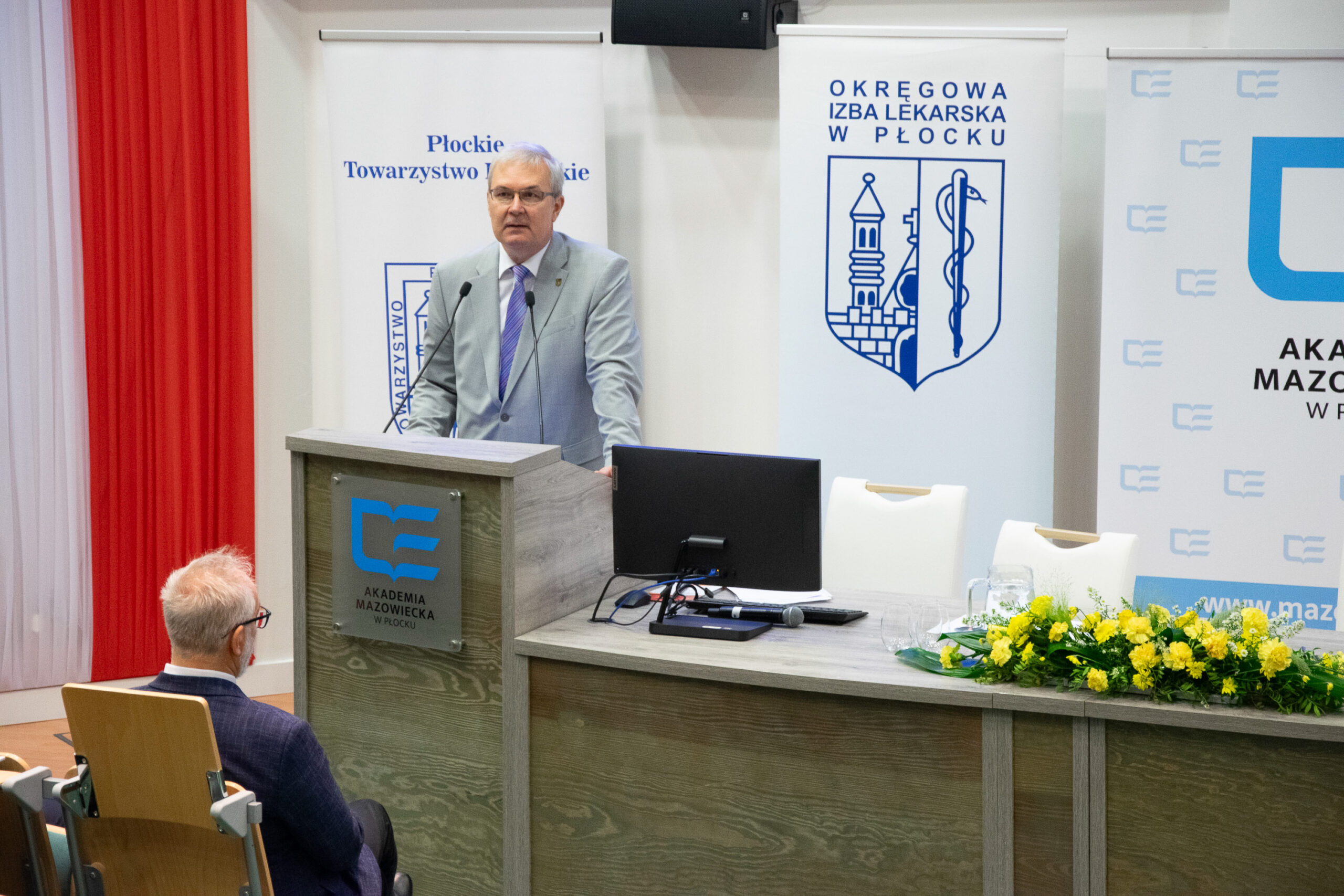 mężczyzna wygłaszający przemówienie przy ambonie do mikrofonów