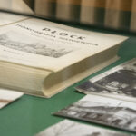 Gablota z artefaktami, stare zdjęcia, księga i zapisy.