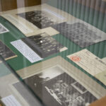 Gablota z artefaktami, stare zdjęcia, księga i zapisy.