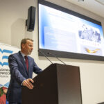 Rektor stojący przy mównicy, za nim rollap